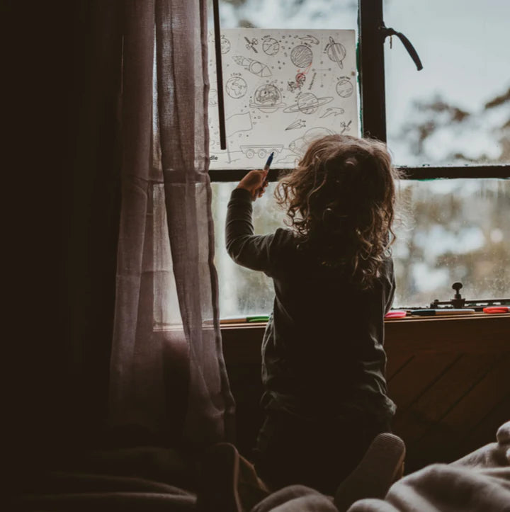 Hey Doodle Outer Space colouring mat, on a window with a child.