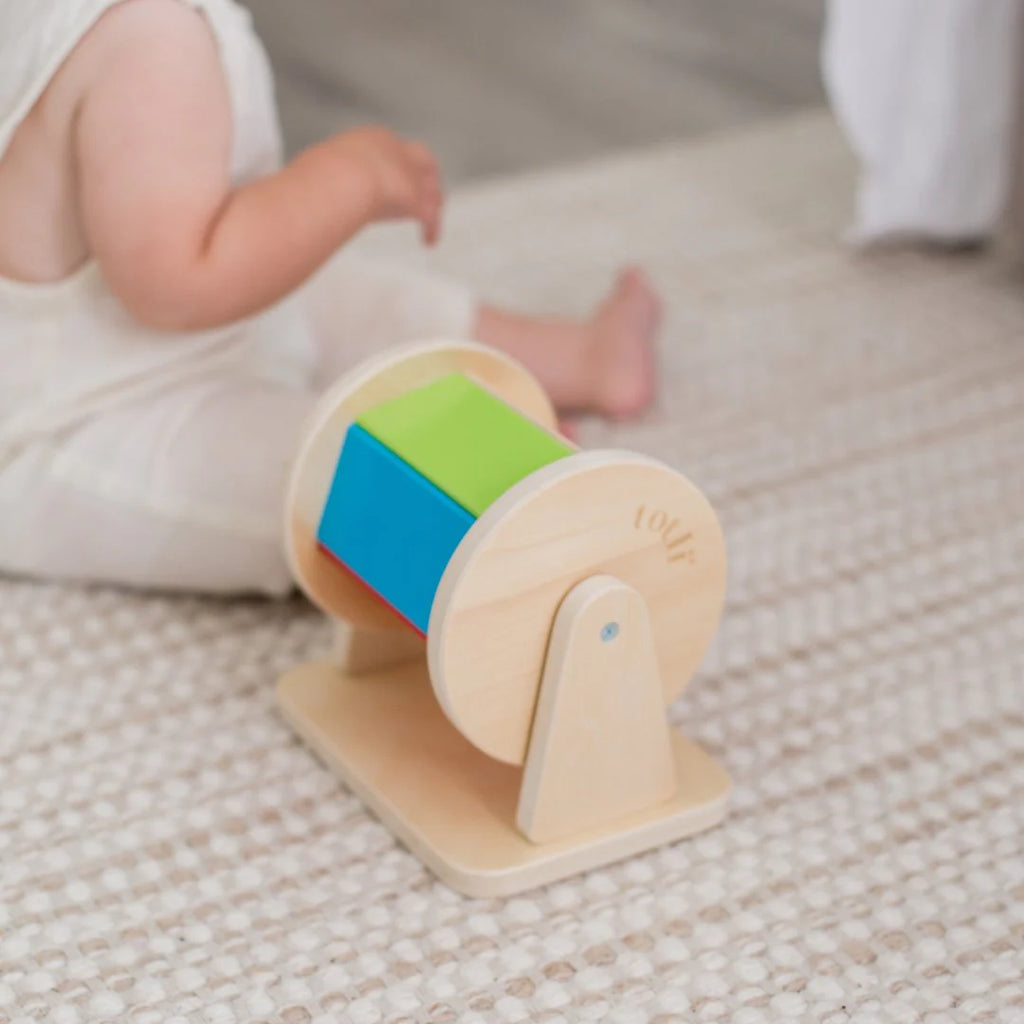 Totli - The Spinning Drum next to a baby sitting on the floor